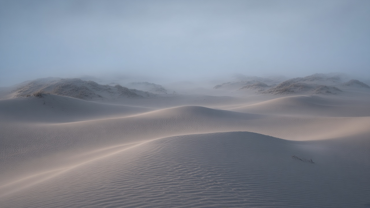Wind-carved sand ripples leading toward a dim blue-grey horizon