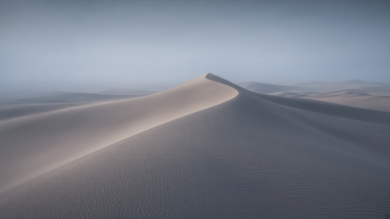 A lone dune crest catching faint morning light above a sea of misty blue-grey dunes