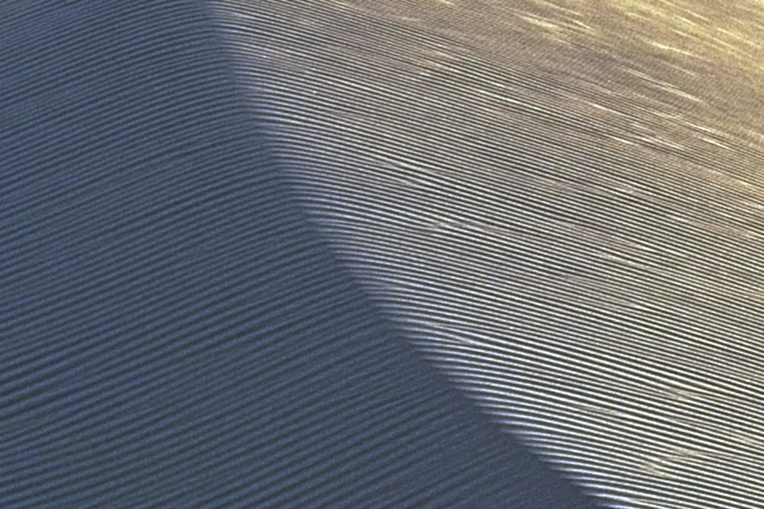 Close view of fine wind ripples crossing a dune in cool blue-grey light, a soft diagonal shadow through the frame
