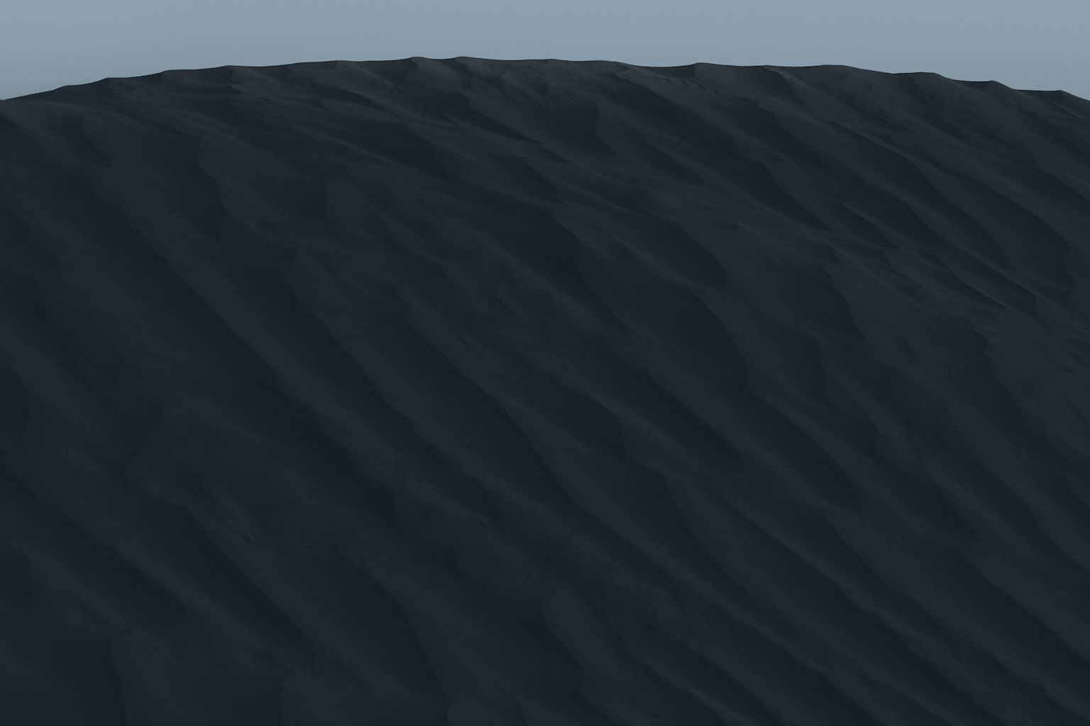A dark rippled sand dune slope in cool navy light beneath a pale grey sky